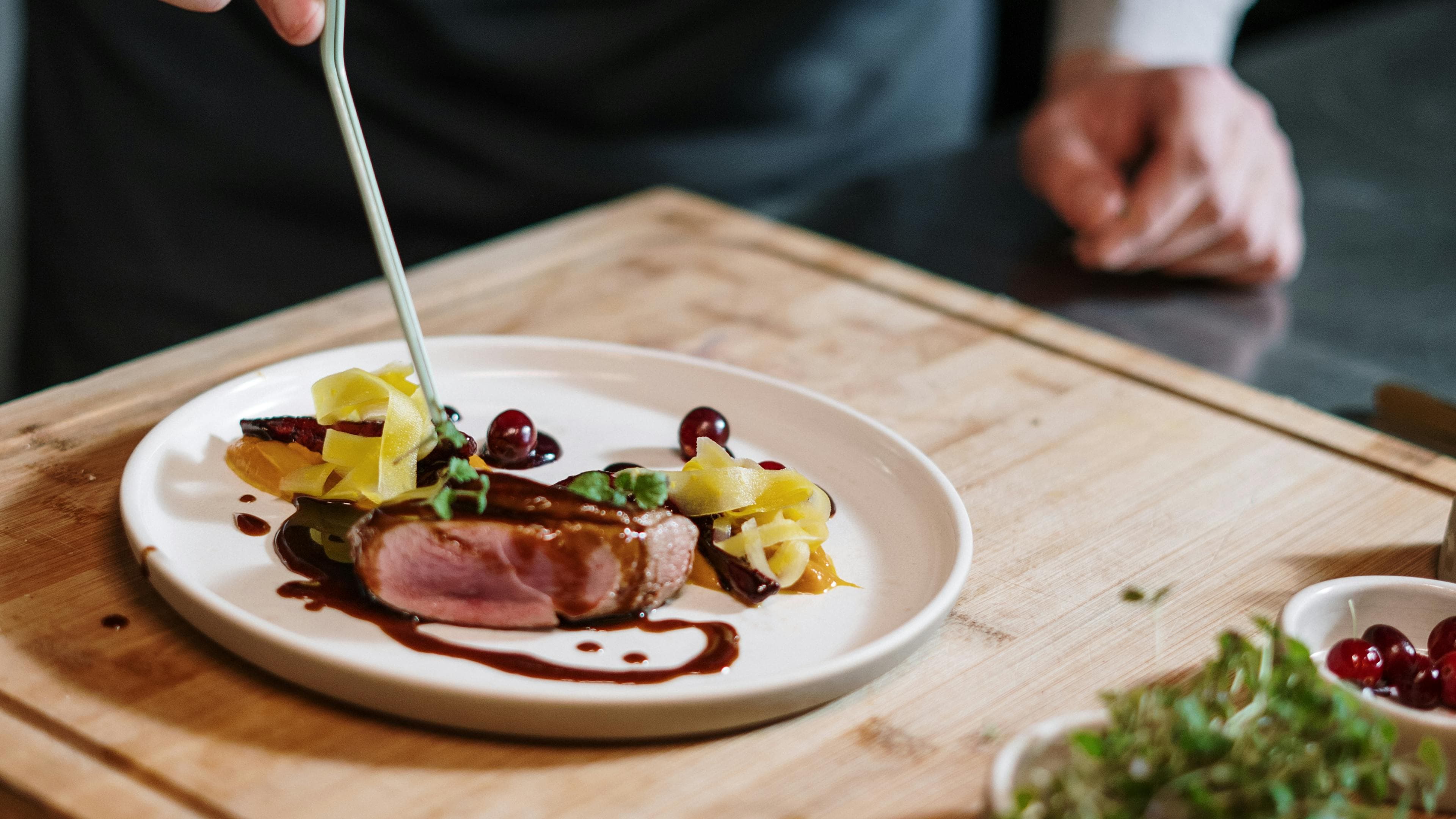 Chef finishing a course with precise garnish work